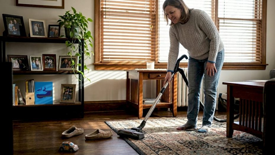 Woman cleaning rug in bright living room