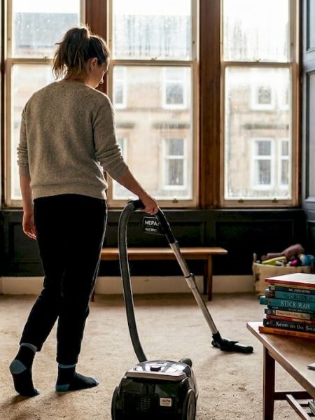 Woman vacuuming living room carpet with HEPA vacuum